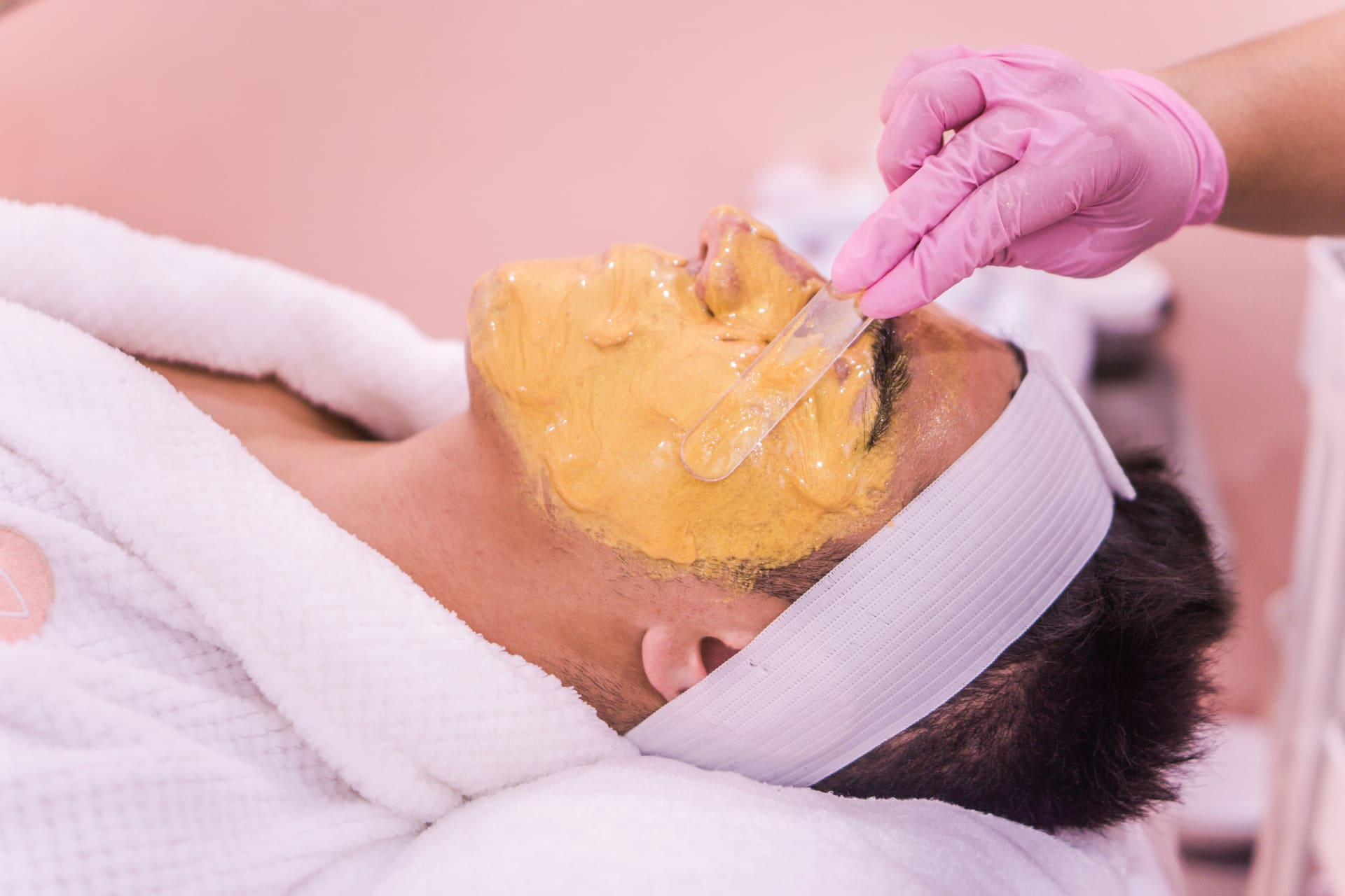 Een goudkleurig masker wordt met een spatel op het gezicht aangebracht